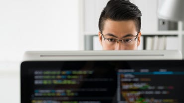 Pensive programmer working on computer in office