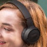 Woman with red hair wearing black over-the-ear headphones and smiling