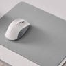 A light grey mouse pad with a white mouse on top of it