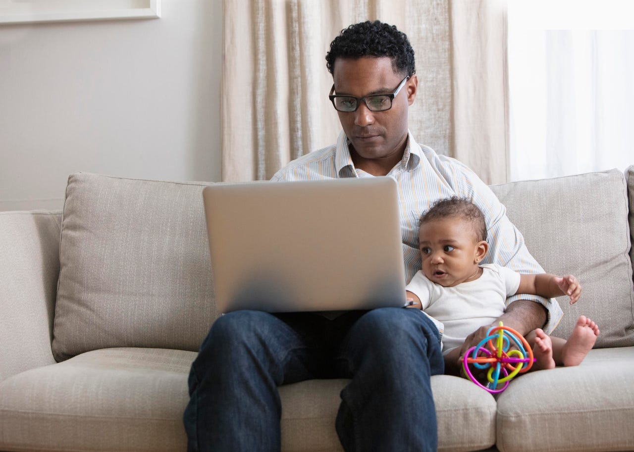 Father working from home and taking care of baby daughter