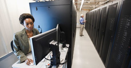 Black woman working on a computer in an office technology room.