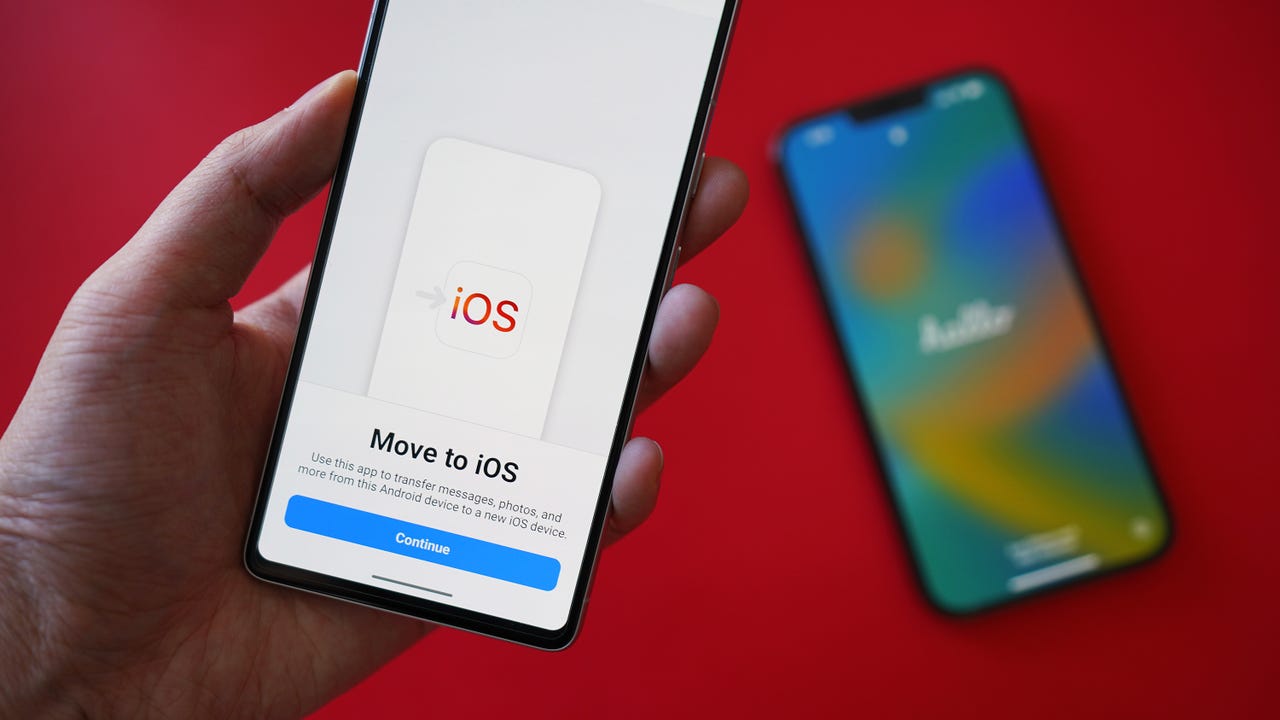 Hand ،lding a p،ne that says Move to iOS, with another p،ne in the background