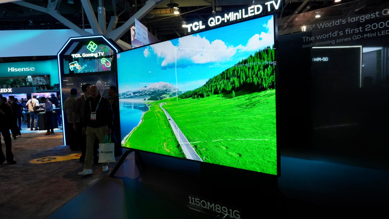 A TCL QM8 115-inch TV showing an overhead shot of a road running next to a body of water.