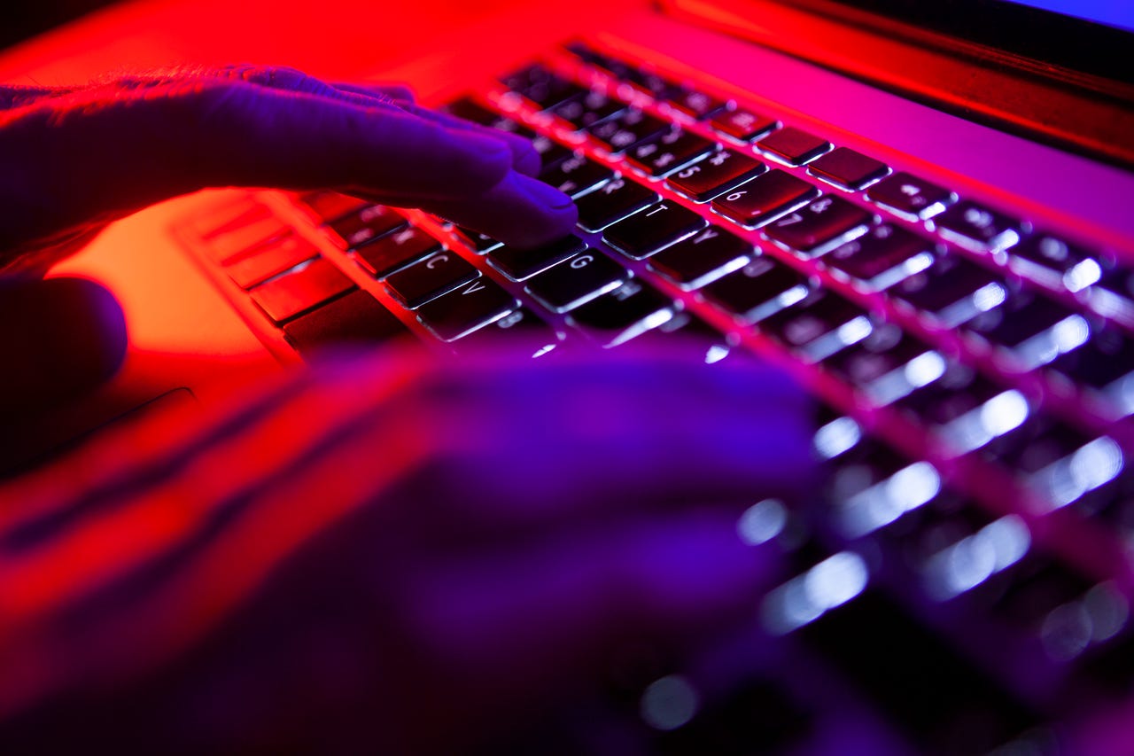 close-up-shot-of-hacker-hands-typing-on-a-keyboard-under-purple-lighting