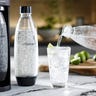 Image of a SodaStream Terra on a marble kitchen counter with a hand pouring sparkling water into a cup.