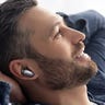 Close-up of a young, bearded man using a pair of Ugreen HiTune X6 earbuds