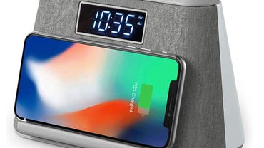 A gray clock radio charges a smartphone