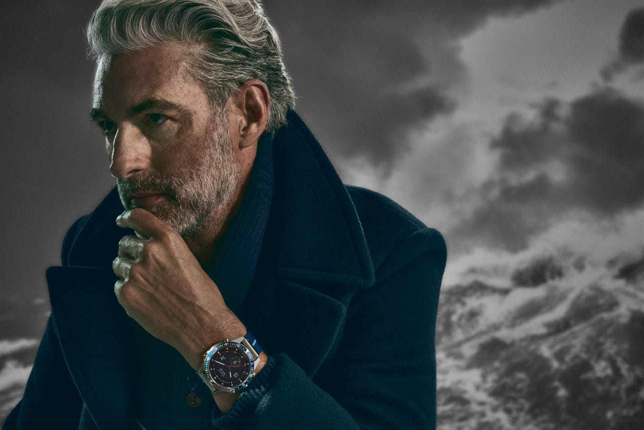 Man in overcoat against a stormy sky, wearing a Garmin MARQ Captain smartwatch.