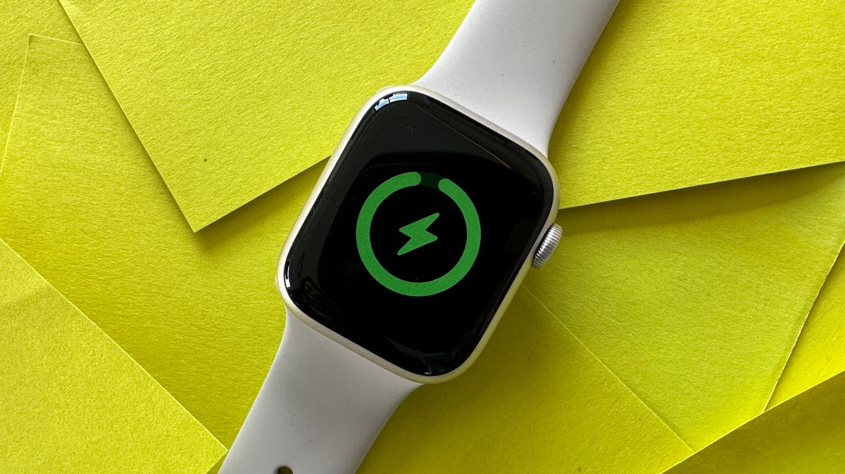 Charging icon on Apple Watch Series 8 on yellow background.