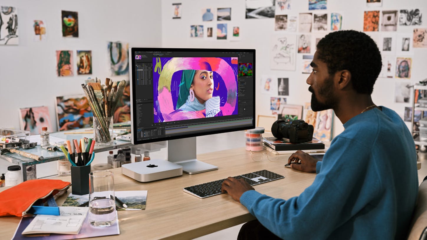 Person using the Mac Mini M2 with Apple Studio Display.
