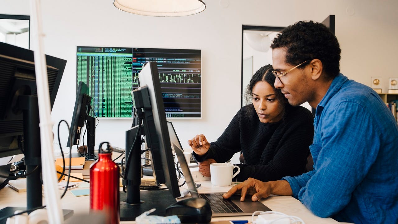Black man and Black woman tech workers looking at a computer together