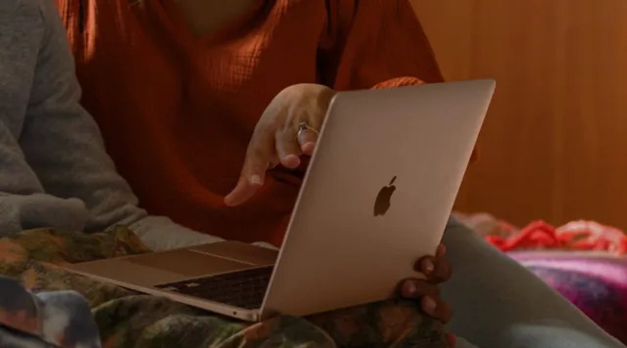 Two people using a Mac.
