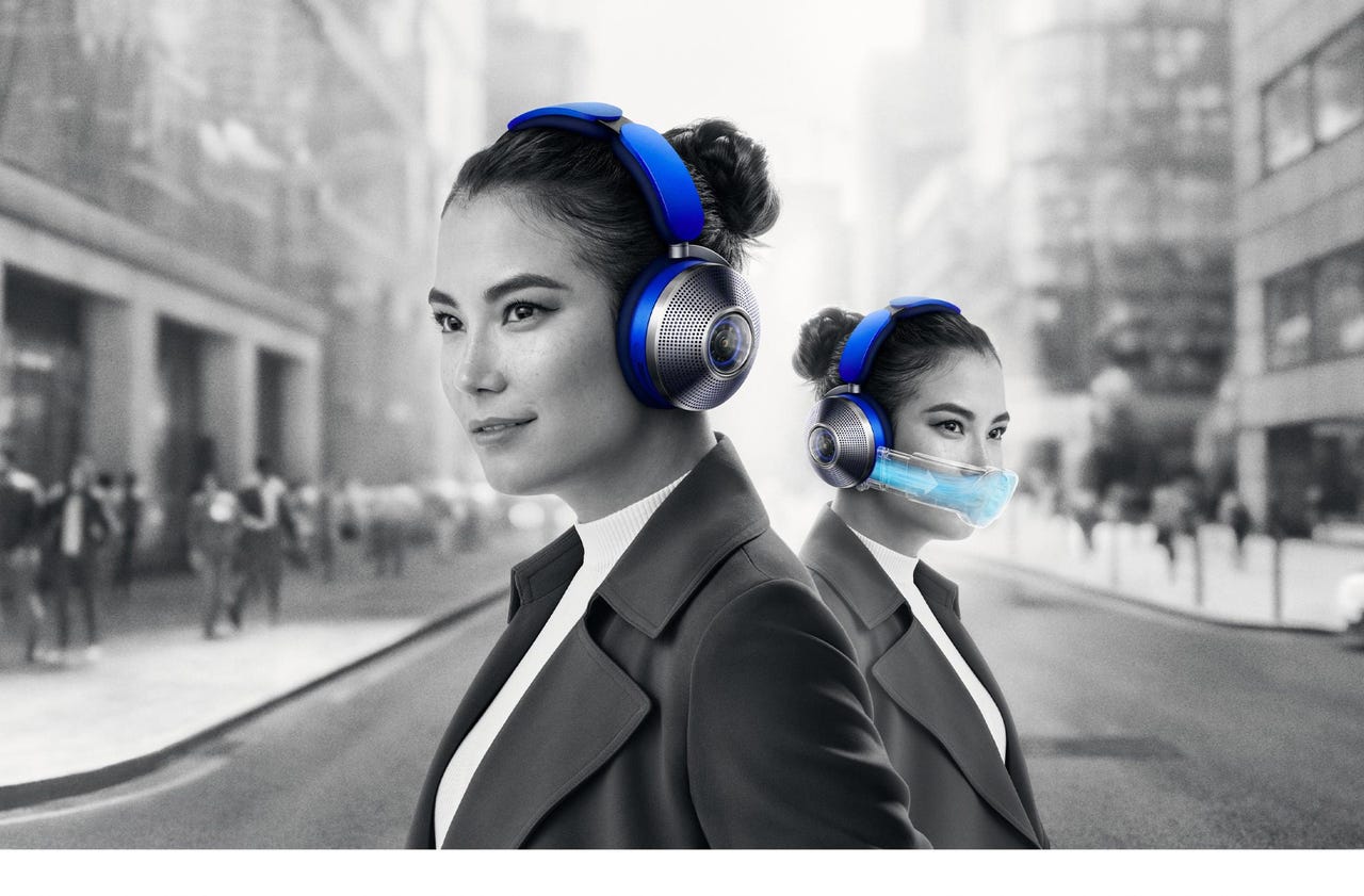 A woman standing in an urban city wearing Dyson Zone air-purifying headphones