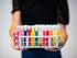 Person holding a colorful tray of beaker vials