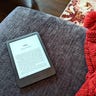 New 2022 Kindle on a blue couch next to a red knit blanket