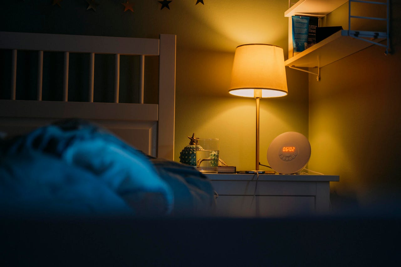 Bedside table with phone charging, lamp, and alarm clock