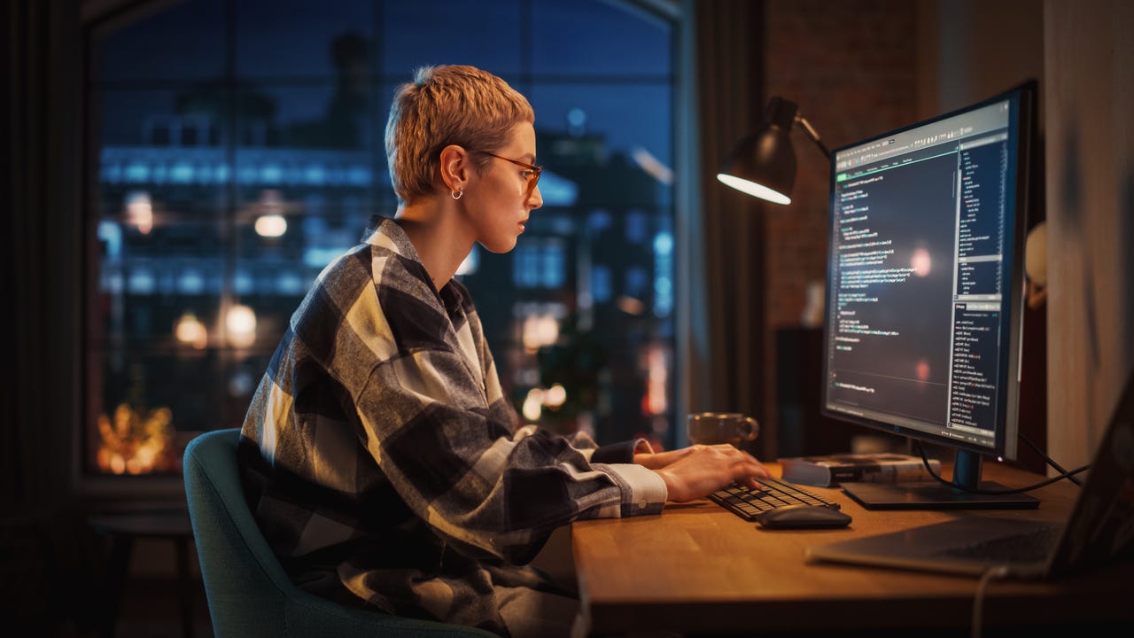 Developer typing code on desktop at night