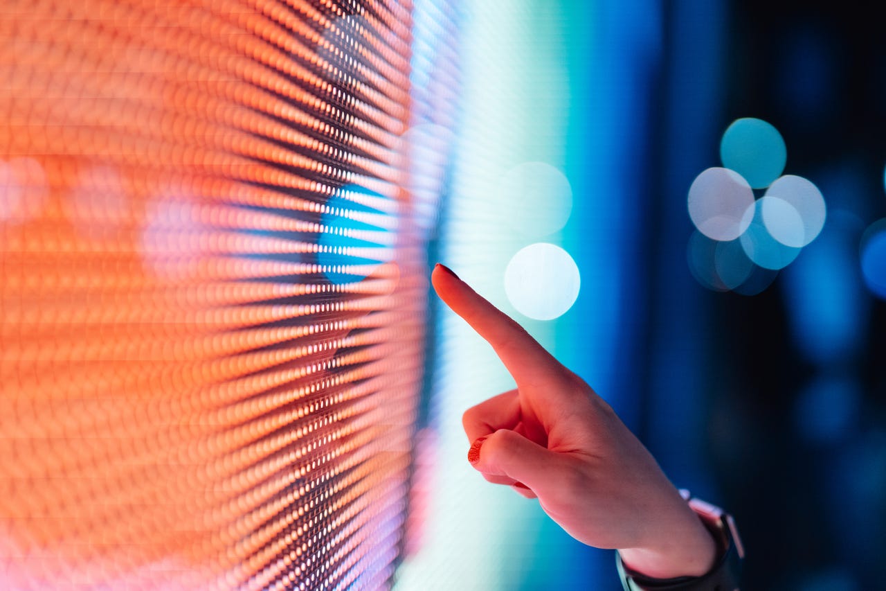 Close-up of female hand touching illuminated digital display in the dark