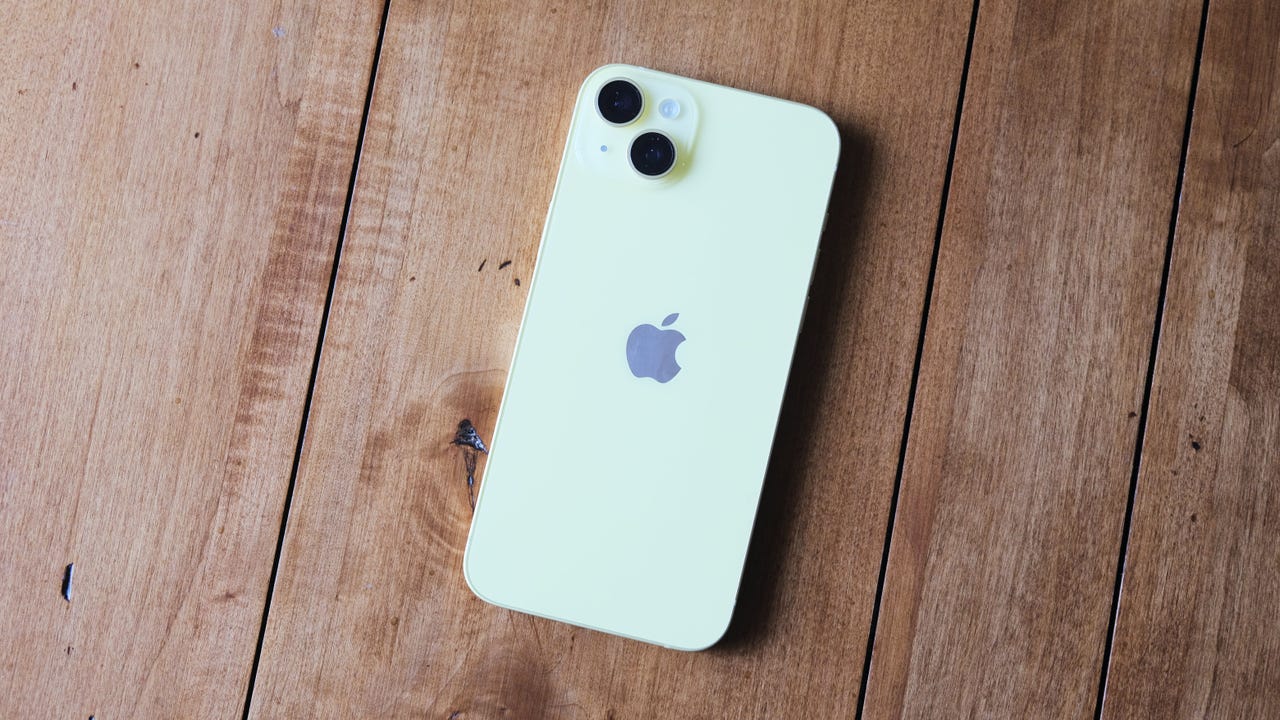 Yellow iPhone 14 Plus on wooden background 
