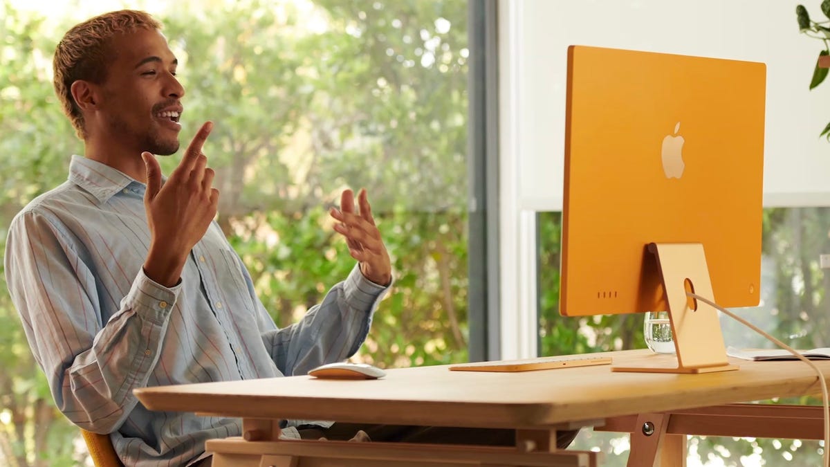 Man being interactive with a yellow iMac on desk