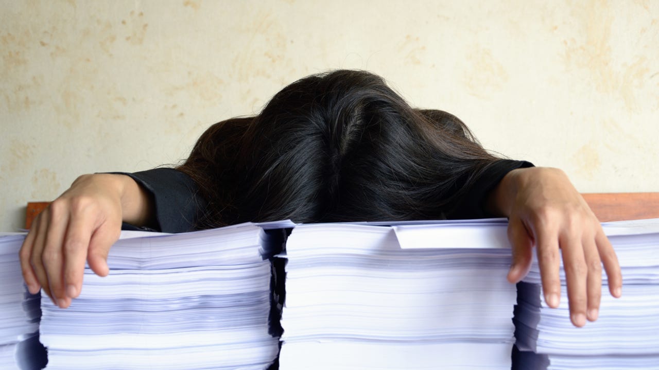 white collar worker or businesswoman tired and sleep at a table with a pile of papers
