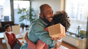 Cheerful African American father getting present from his daughter, celebrating. - stock photo