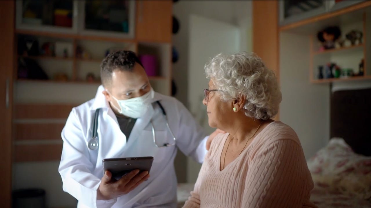 Healthcare worker with tablet visiting a patient at their home