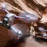 Two DJI FPV drones flying through a windswept canyon