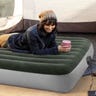 Woman laying on a green air mattress on her stomach holding a cup