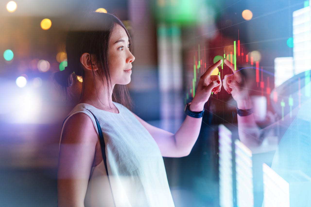 A woman touching a futuristic digital display.