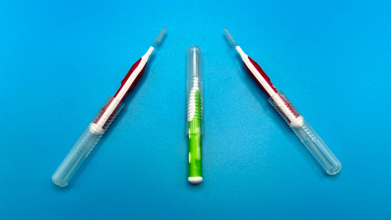 Three interdental brush tools, one with a transparent cap