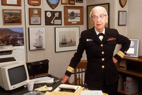 Grace hopper in a military uniform standing next to a computer