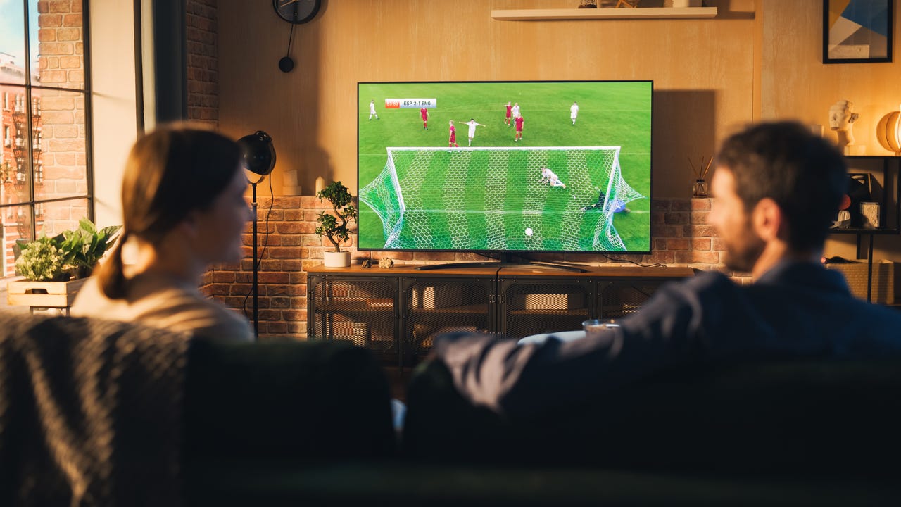 Man and woman watching soccer on a TV