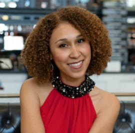 Krystal Covington, a woman with shoulder-length, curly hair, smiles for the camera.