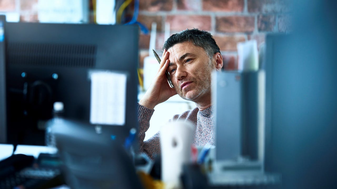 male desk worker looking at his computer screen with a stressed and tired expression